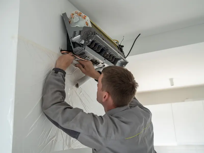 installateur fixant unite murale climatisation reversible logement m Installateur fixant l'unité murale d'une climatisation réversible dans un logement