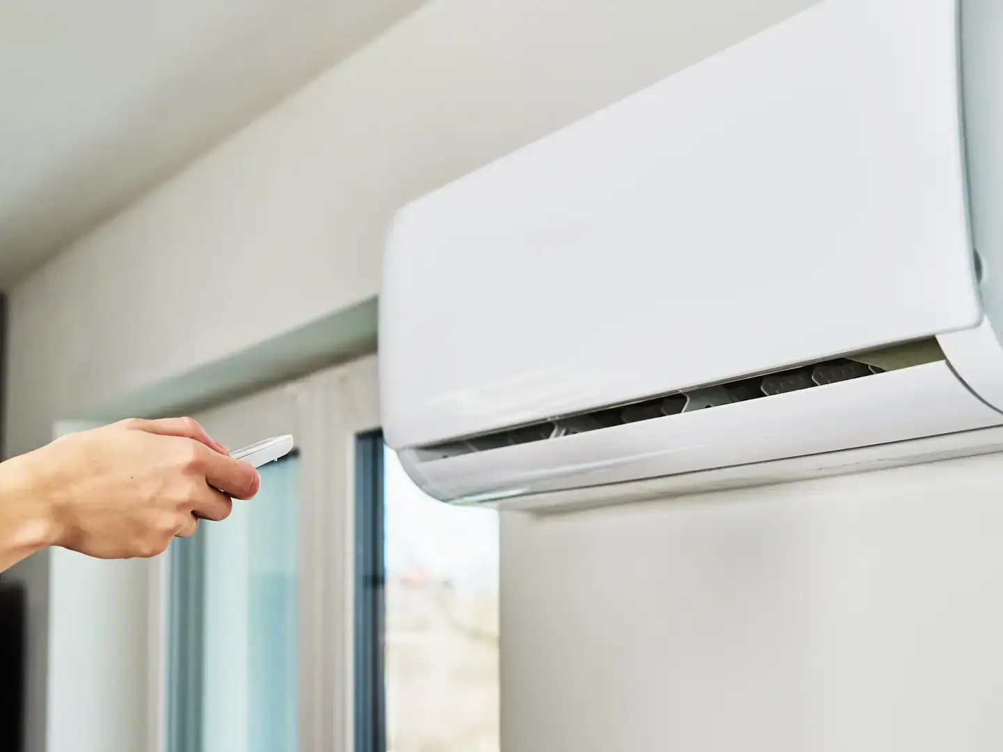 Personne réglant sa climatisation murale avec la télécommande