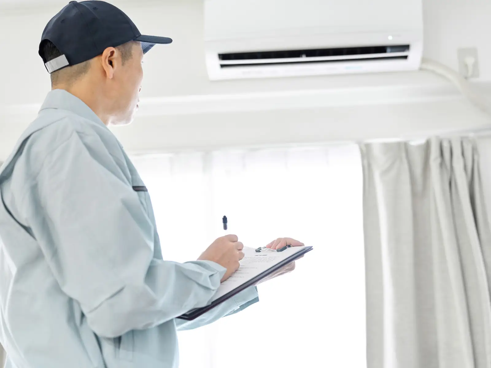 Technicien consignant les contrôles effectués lors de la visite d'entretien d'une climatisation
