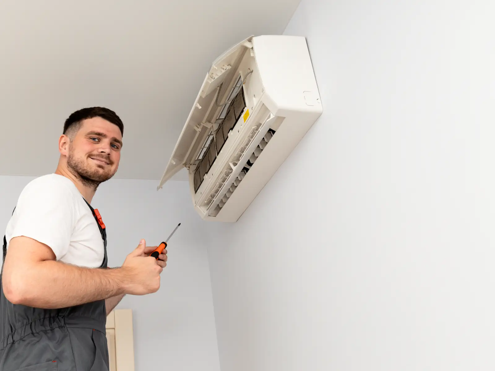 Technicien démontant une unité intérieure de climatisation pour la réparer
