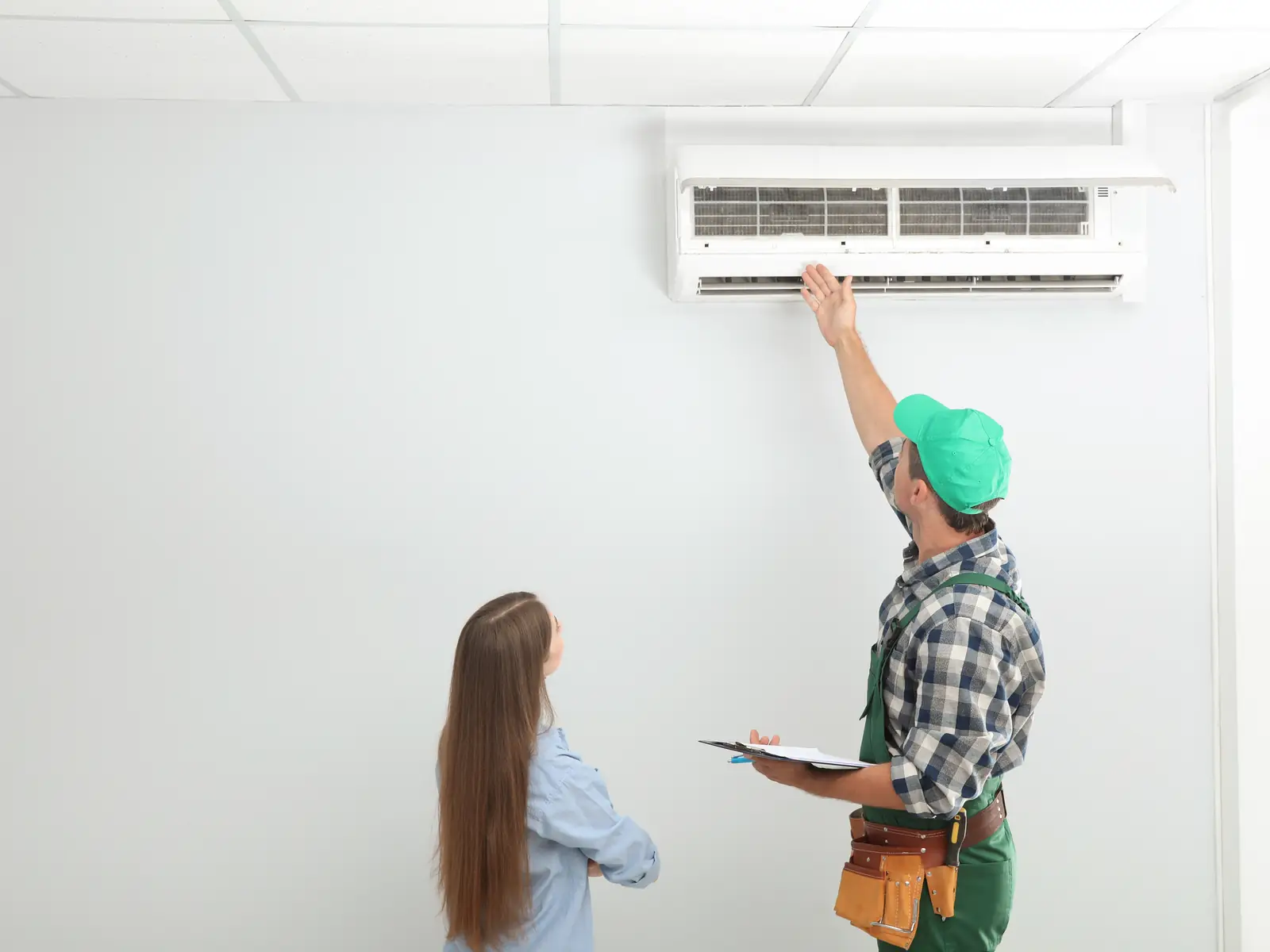 Technicien expliquant à une cliente les points d'entretien de sa climatisation avant la saison chaude