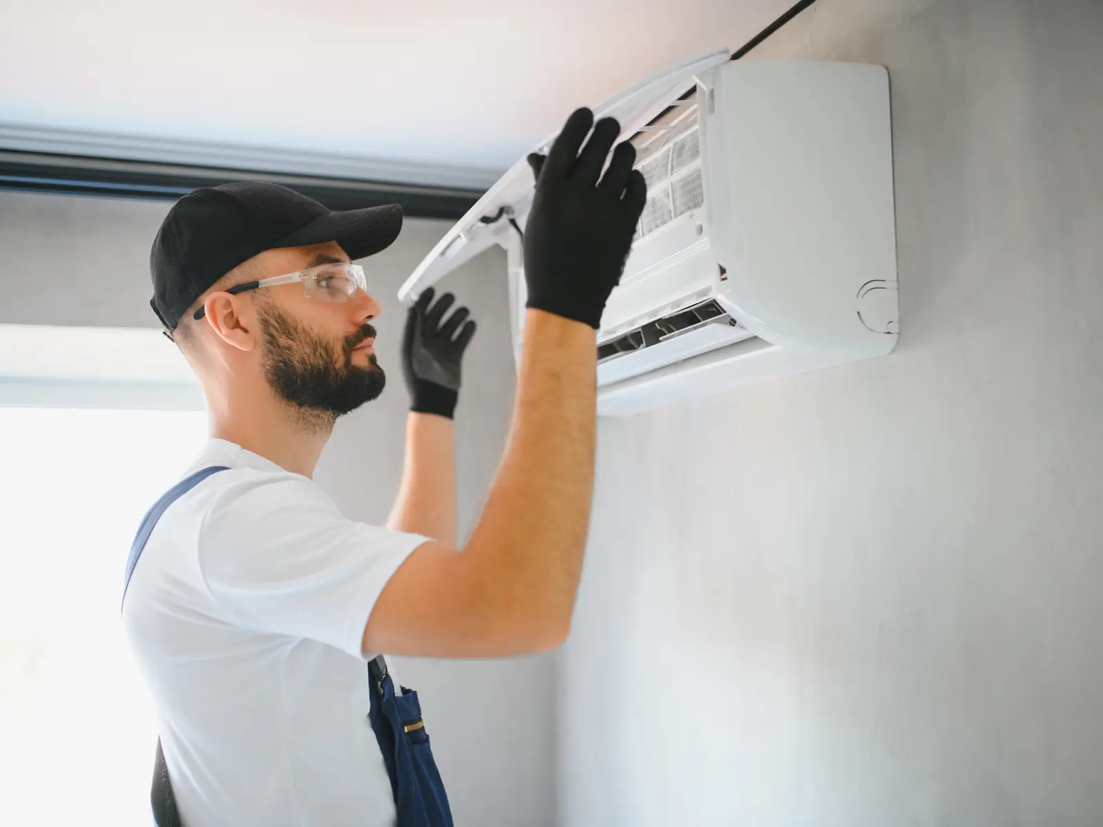 Technicien intervenant sur un climatiseur mural pour localiser l'origine d'un bruit