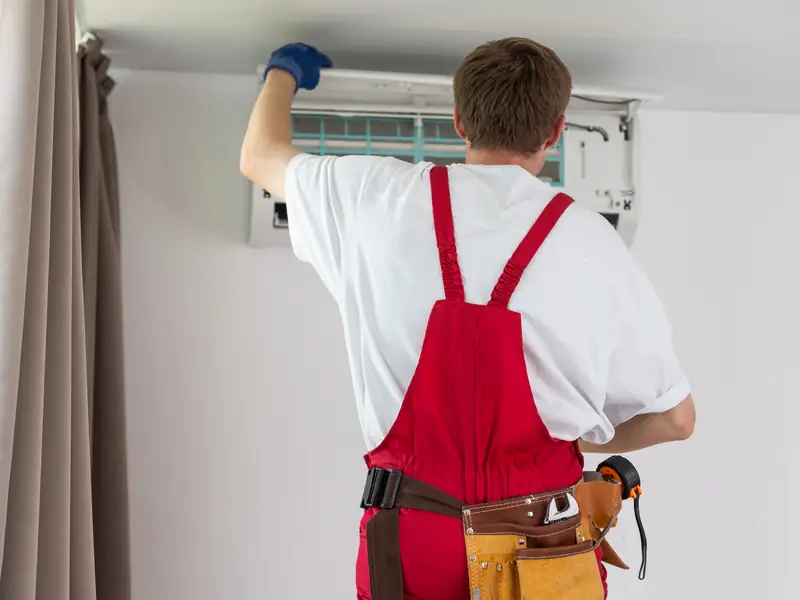 technicien verifiant climatisation murale installee chambre m Technicien vérifiant une climatisation murale installée dans une chambre