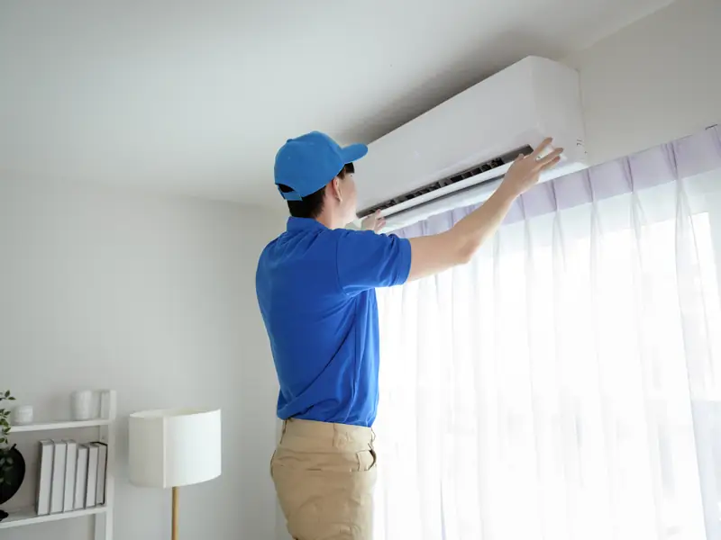 Vérification d'une unité murale de climatisation par un technicien lors d'un contrôle